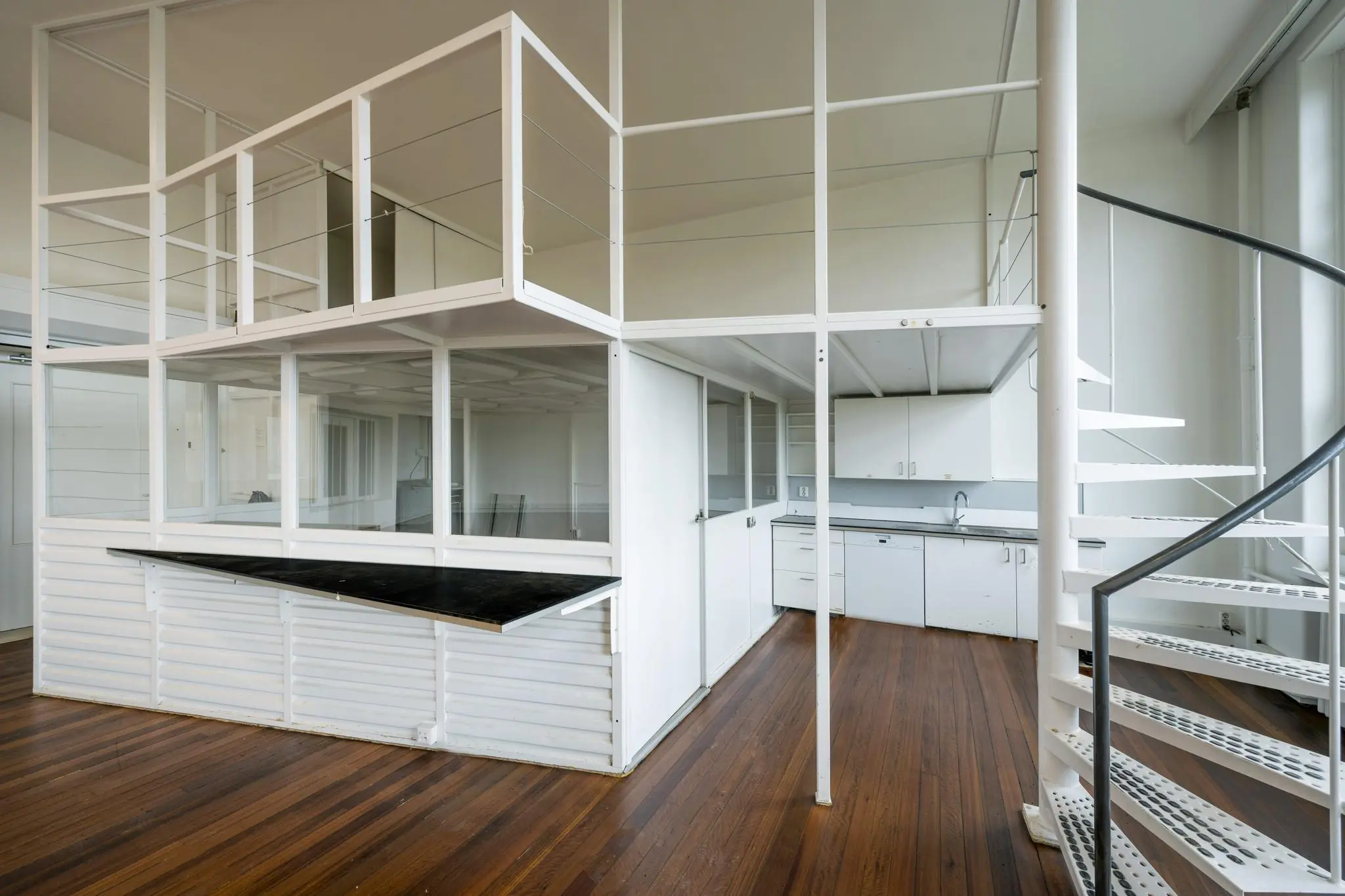 Modern wit interieur met een open entresol, houten vloer en een spiraaltrap in een woning aan het WG-plein.