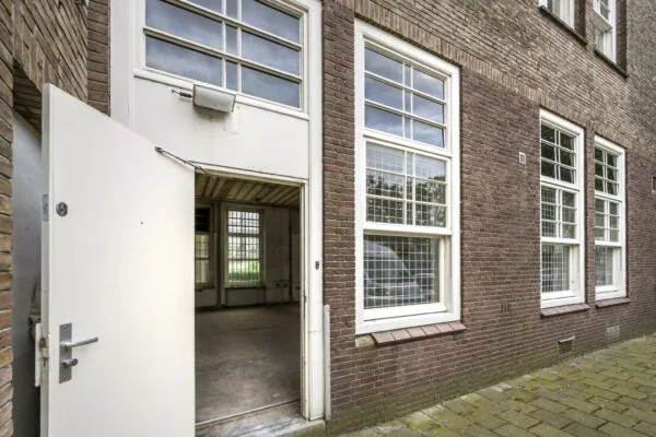 Openstaande witte deur naar een lege ruimte in een bakstenen gebouw aan het WG-plein.