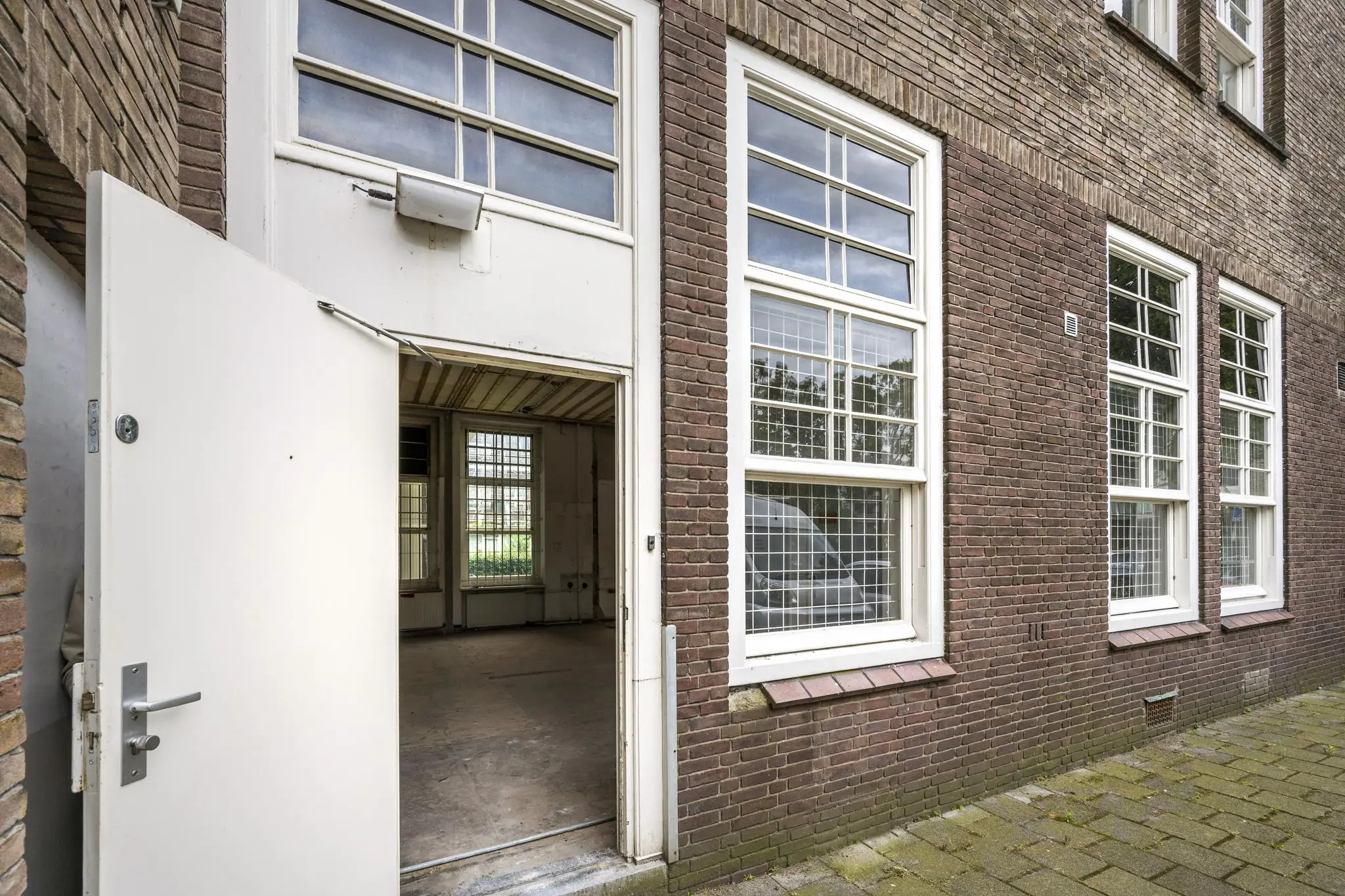 Openstaande witte deur naar een lege ruimte in een bakstenen gebouw aan het WG-plein.