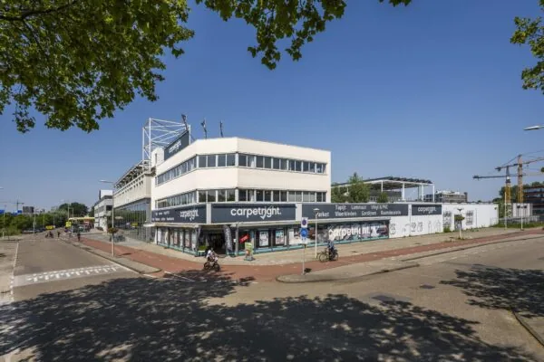 Winkelpand van Carpetright aan de Anthony Fokkerweg op een zonnige dag met passerende fietsers.