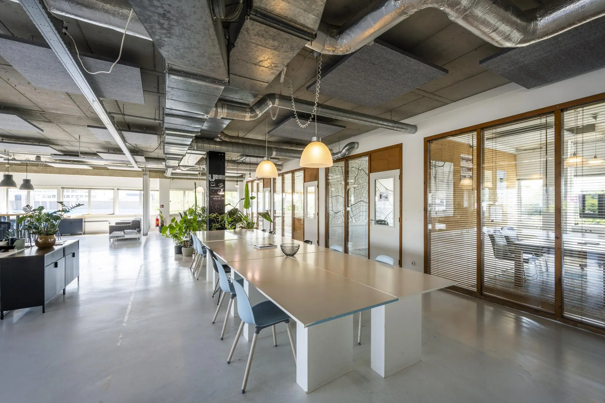 Moderne kantoorruimte aan de Anthony Fokkerweg met een lange vergadertafel, industriële plafonduitvoering en veel natuurlijk licht.