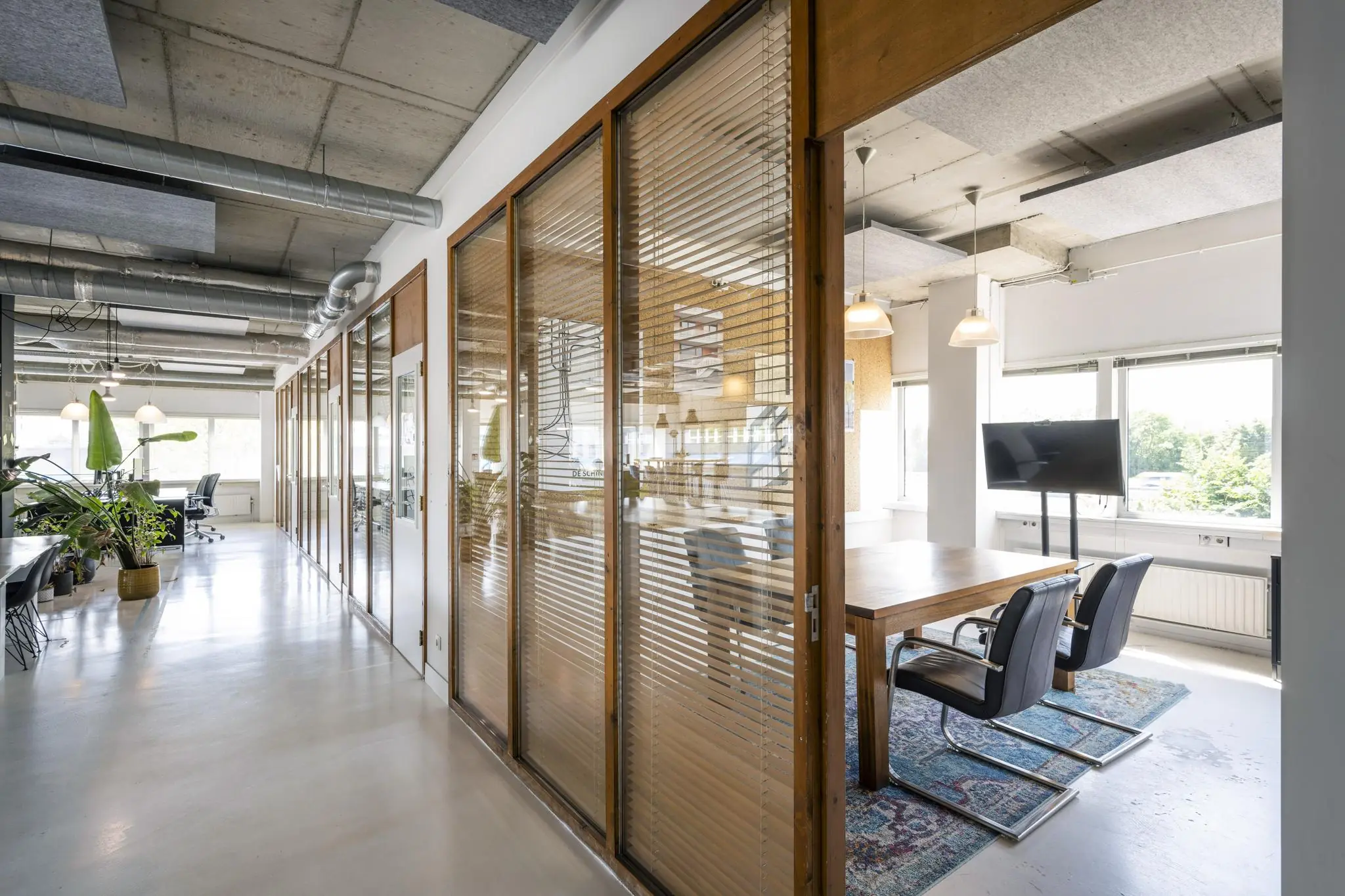 Moderne kantoorruimte aan de Anthony Fokkerweg met glazen vergaderruimte, houten details en grote ramen.
