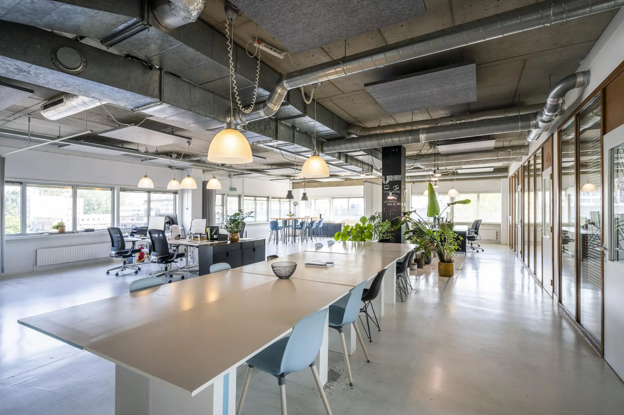 Modern en licht kantoorinterieur aan de Anthony Fokkerweg met open werkplekken, vergadertafels en veel groen.