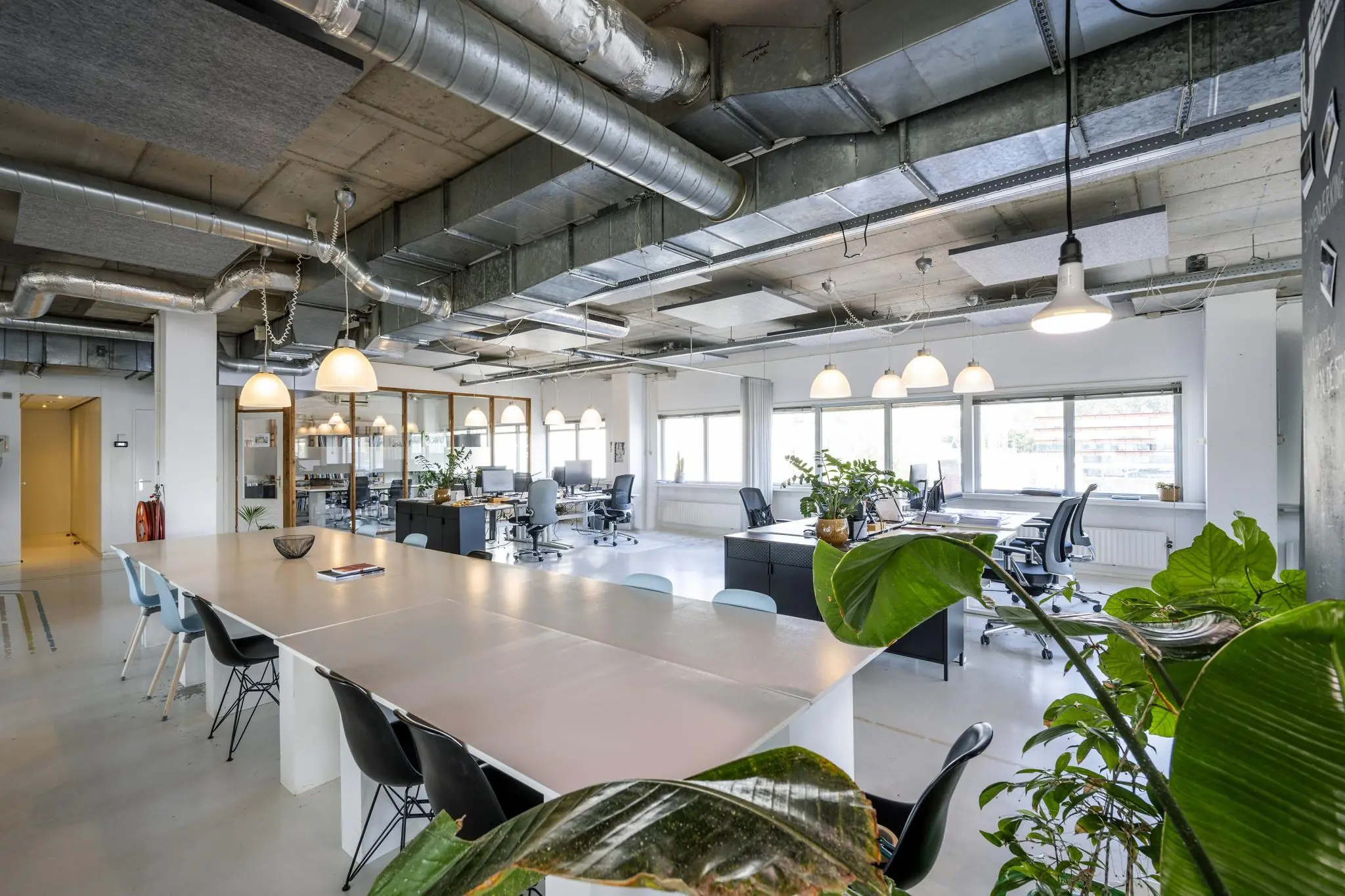 Moderne en lichte kantooruimte aan de Anthony Fokkerweg met open werkplekken, grote ramen en groene planten.