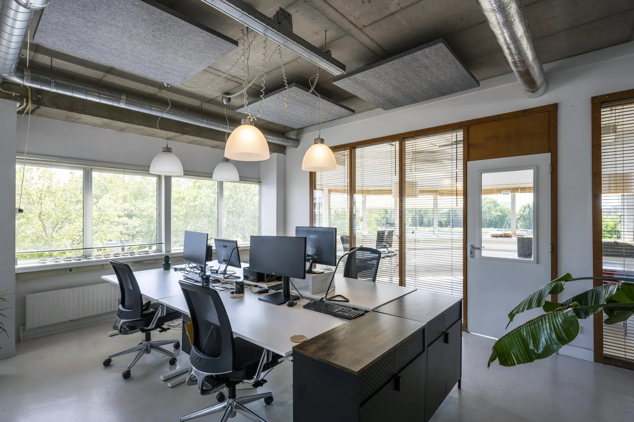 Modern ingericht kantoor aan de Anthony Fokkerweg met werkplekken, computers en grote ramen met uitzicht op groen.