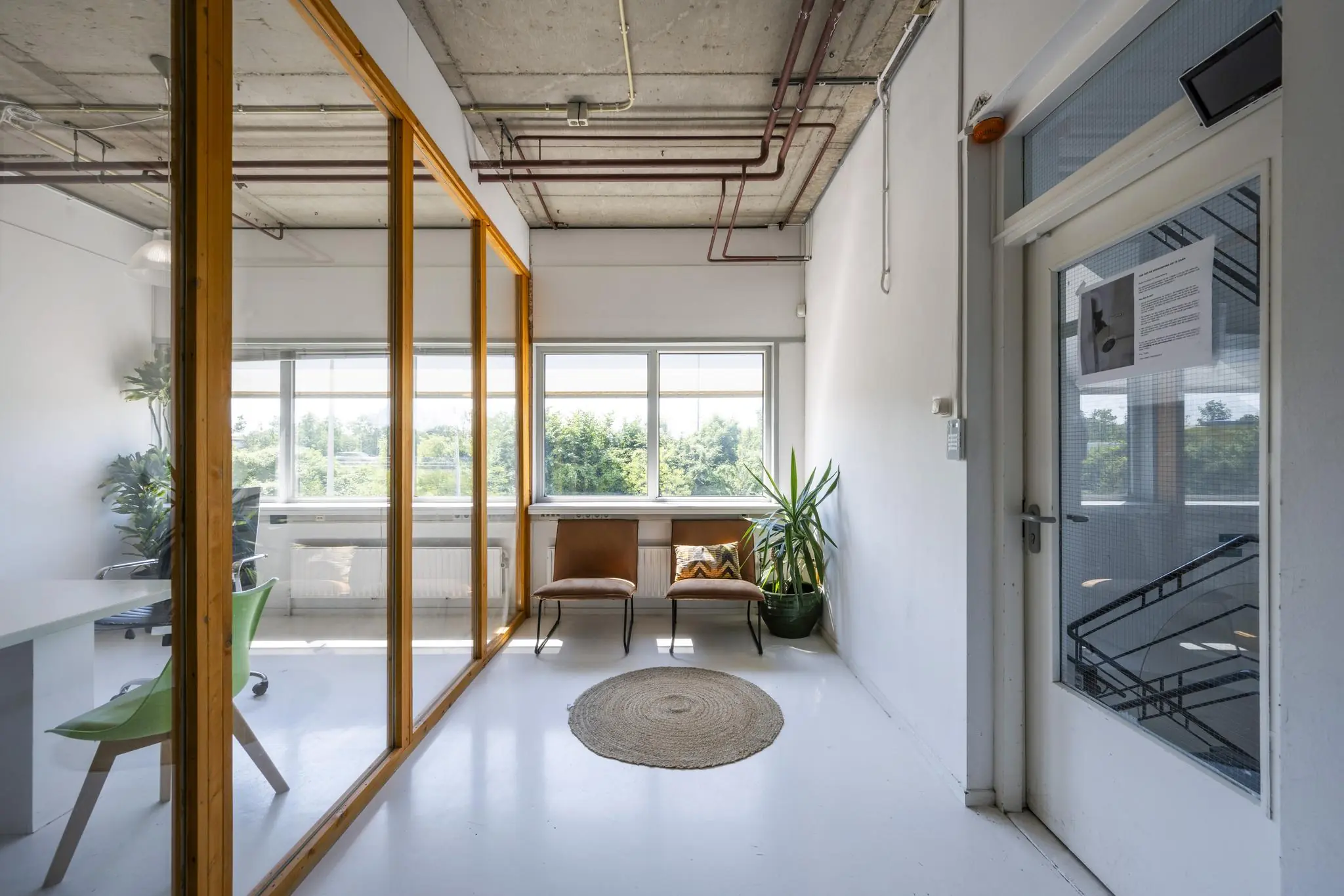 Wachtruimte met twee stoelen, een plant en een groot raam in een licht kantoorpand aan de Anthony Fokkerweg.