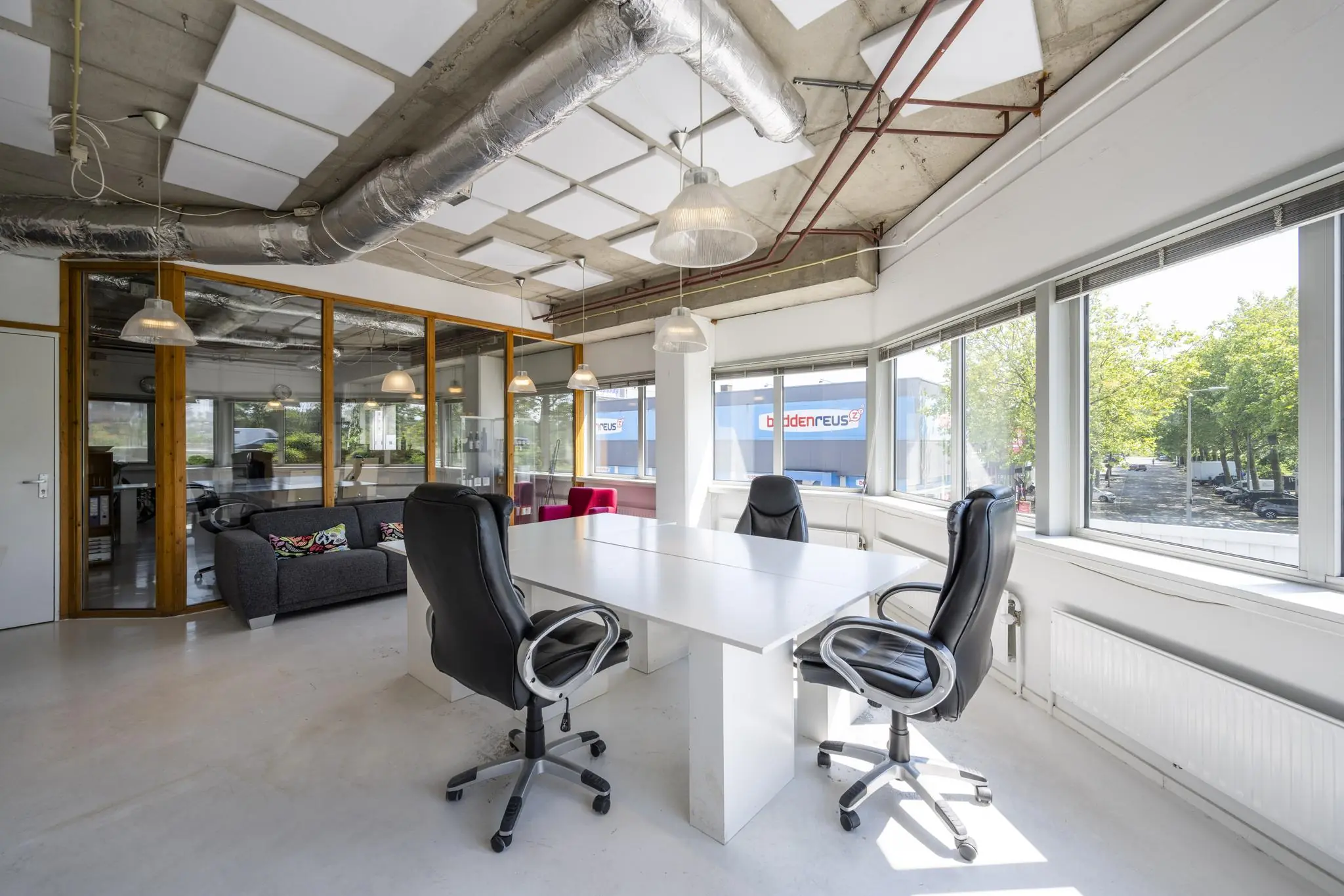 Moderne kantoorruimte aan de Anthony Fokkerweg met vergadertafel, bureaustoelen en grote ramen met uitzicht op het gebouw van Beter Bed.