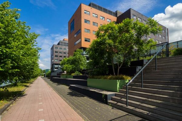 Moderne kantoorgebouwen aan de Ringwade in Nieuwegein met groene beplanting en een brede trap naast een wandelpad.