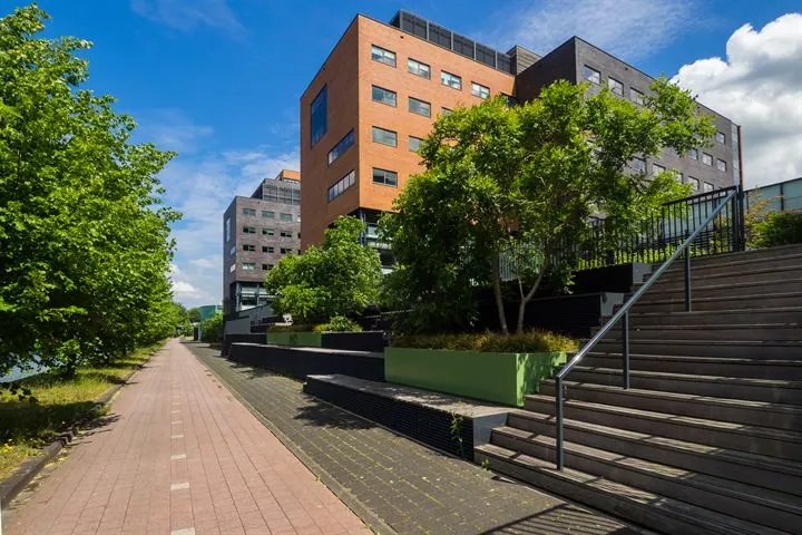 Moderne kantoorgebouwen aan de Ringwade in Nieuwegein met groene beplanting en een brede trap naast een wandelpad.