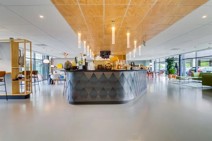 Moderne koffibar met metalen front en hanglampen in een ruim, licht kantoorpand aan de Ringwade.