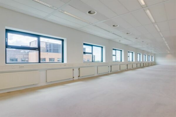 Lichte, lege kantoorruimte aan de Ringwade met een rij grote ramen en systeemplafond.