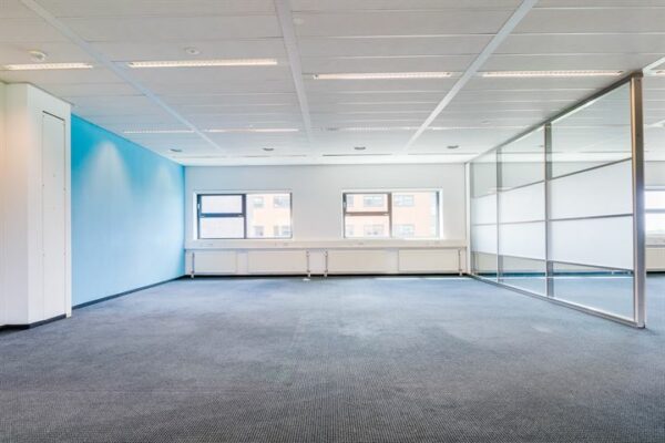 Leeg, modern kantoor met blauwe accentmuur en glazen scheidingswand aan de Ringwade.
