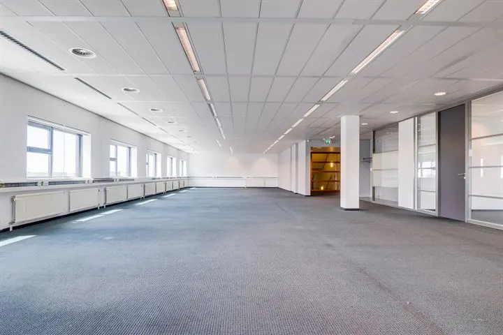 Ruime, lege kantoorruimte met systeemplafond, grote ramen en glazen scheidingswanden aan Ringwade.