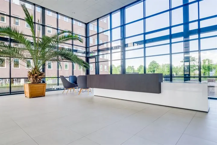 Moderne, lichte ontvangsthal van kantoorgebouw Ringwade met grote raampartijen, balie en zitgedeelte.