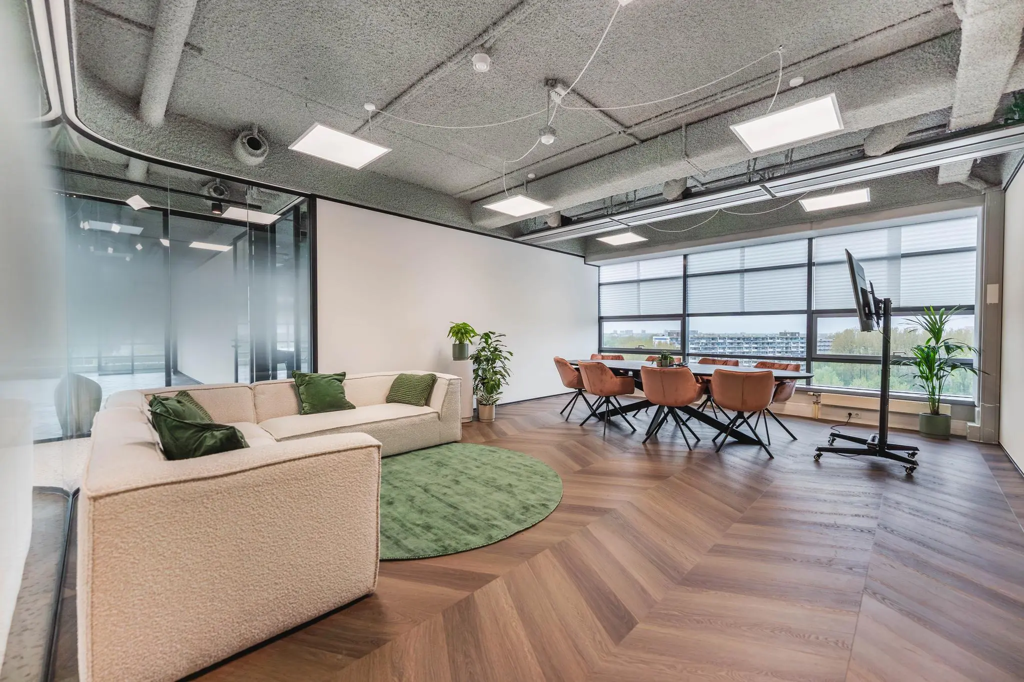 Moderne vergaderruimte aan de Joop Geesinkweg met een zithoek, grote ramen en een vergadertafel met leren stoelen.