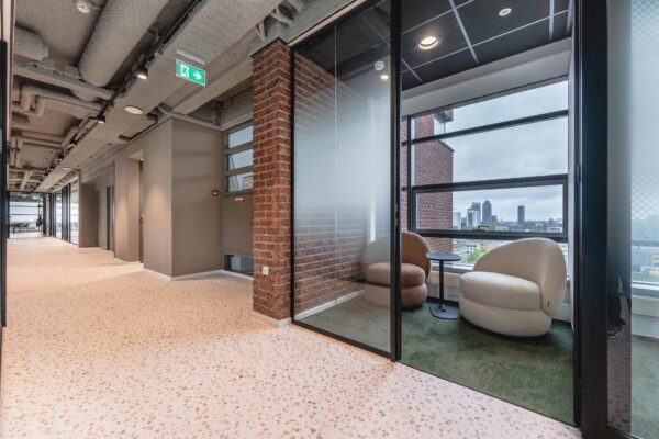 Moderne kantoorruimte aan de Joop Geesinkweg met een glazen vergaderruimte en uitzicht op de skyline van Amsterdam.