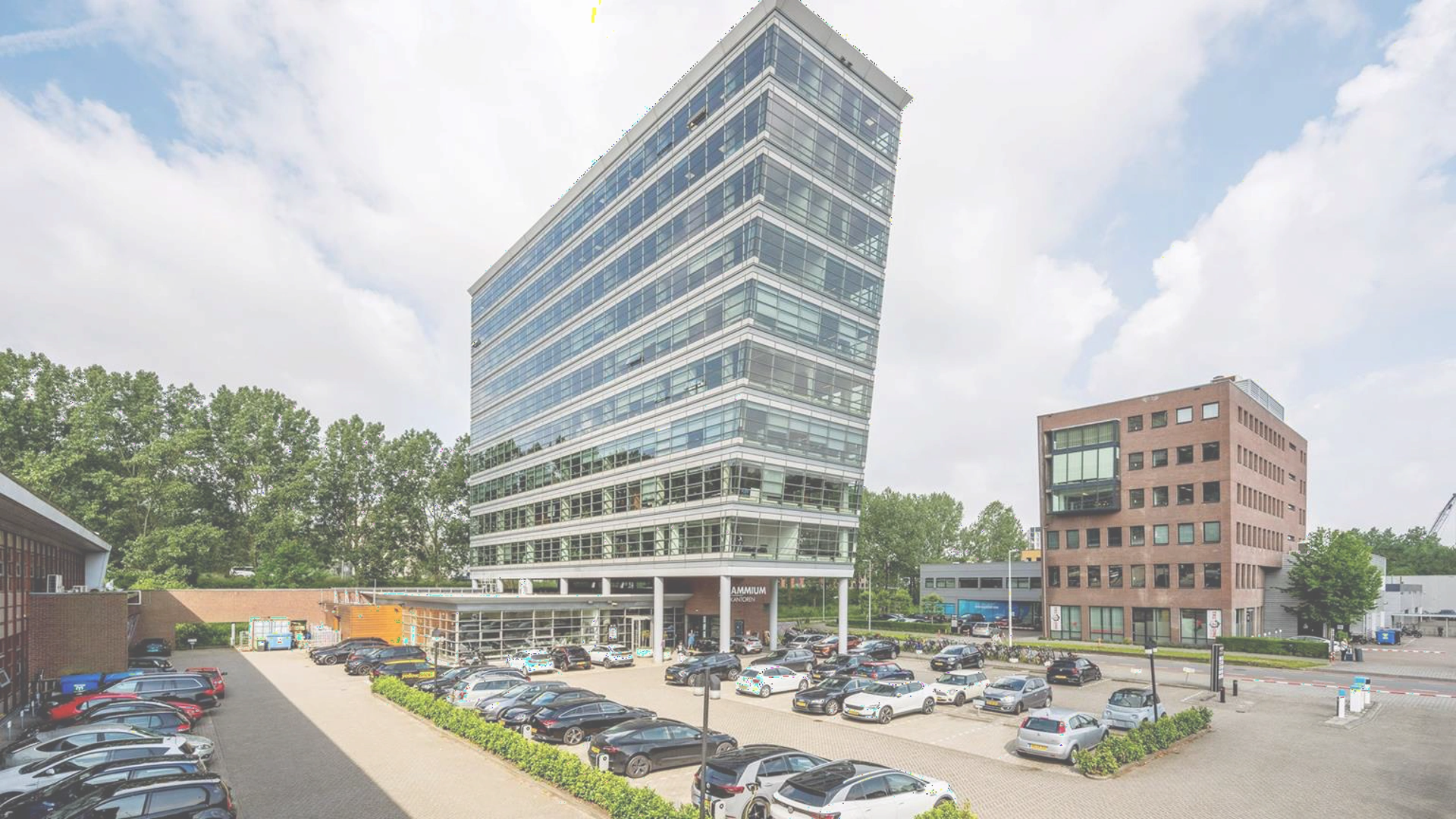 Kantoorgebouw aan de Joop Geesinkweg met parkeergarage en omliggende bebouwing.