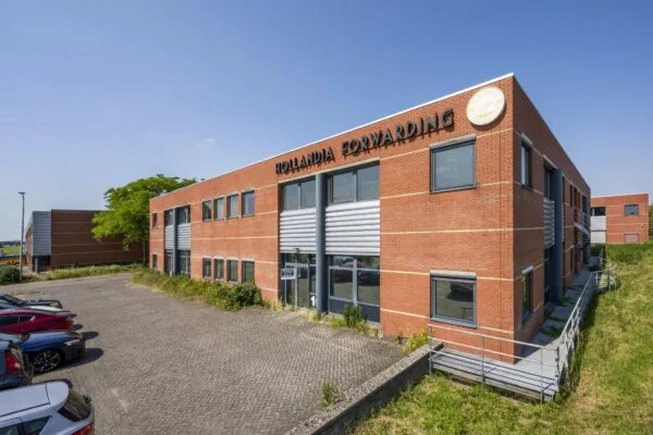 Modern bedrijfspand van Hollandia Forwarding aan de Breguetlaan, met rode bakstenen gevel en parkeerterrein.