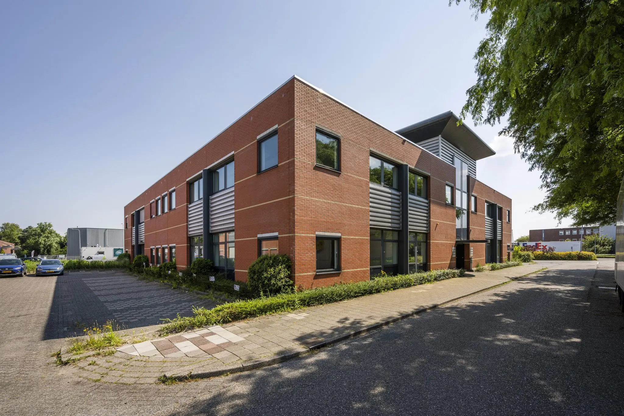 Modern kantoorgebouw aan de Breguetlaan met rode bakstenen gevel en parkeerplaatsen aan de zijkant.