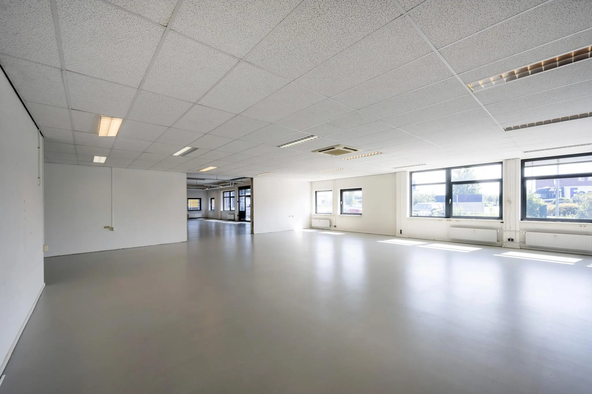 Lichte, lege kantoorruimte aan de Breguetlaan met grote ramen en systeemplafond.