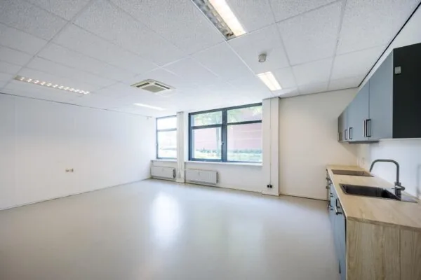 Lichte, lege kantoorruimte aan de Breguetlaan met keukenblok en grote ramen.