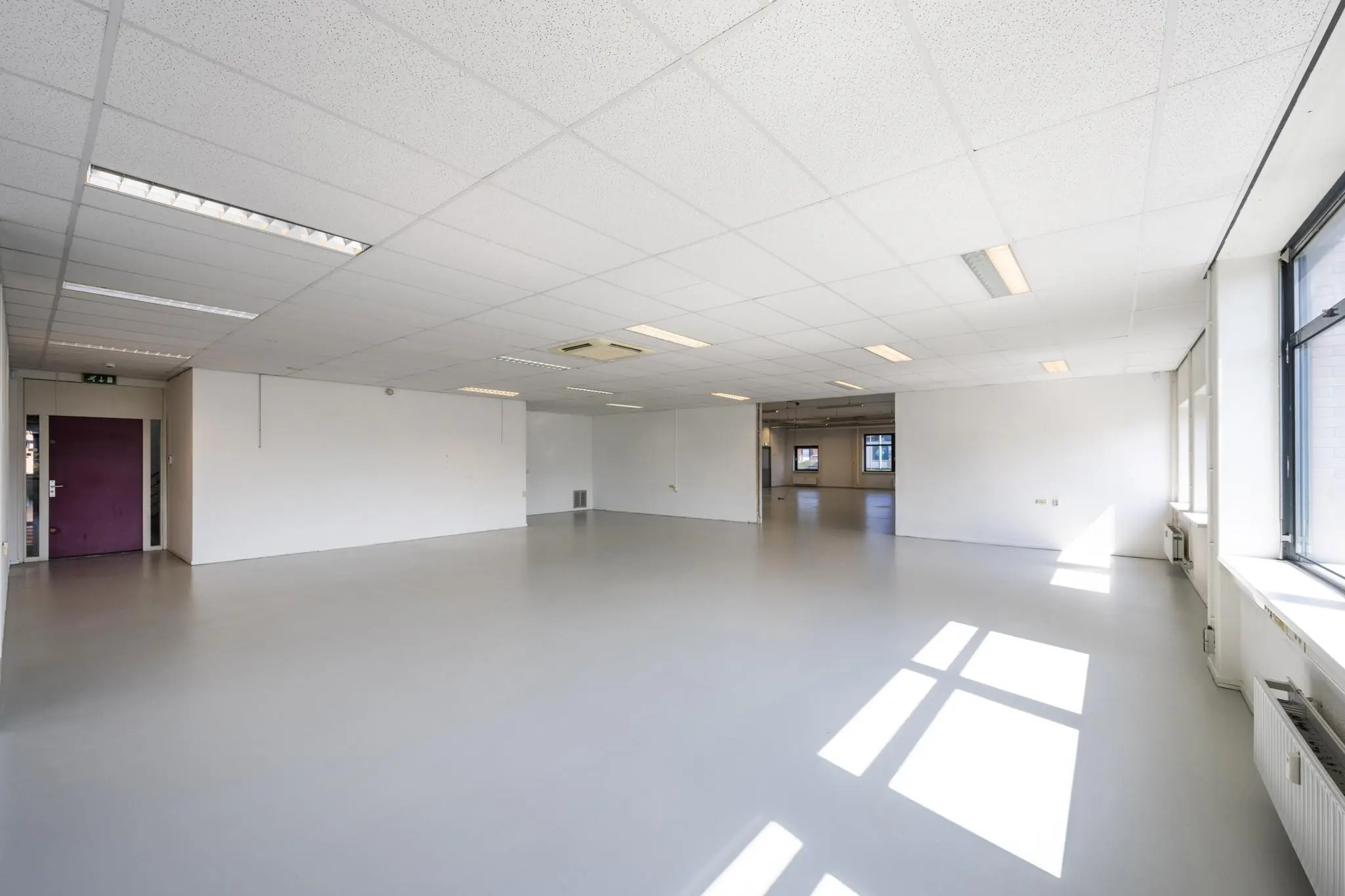 Lichte, lege kantoorruimte aan de Breguetlaan met systeemplafond en grote ramen.