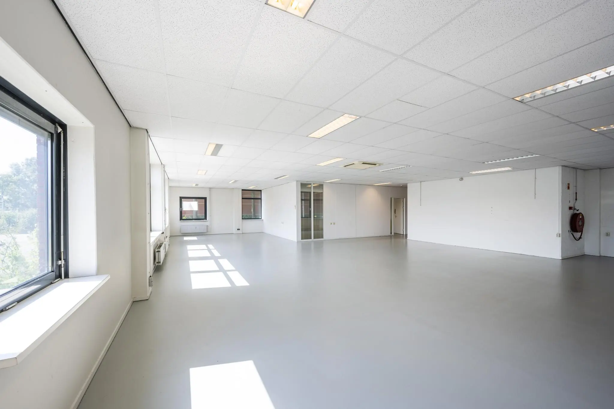 Licht en ruim leeg kantoor aan de Breguetlaan met grote ramen en systeemplafond.