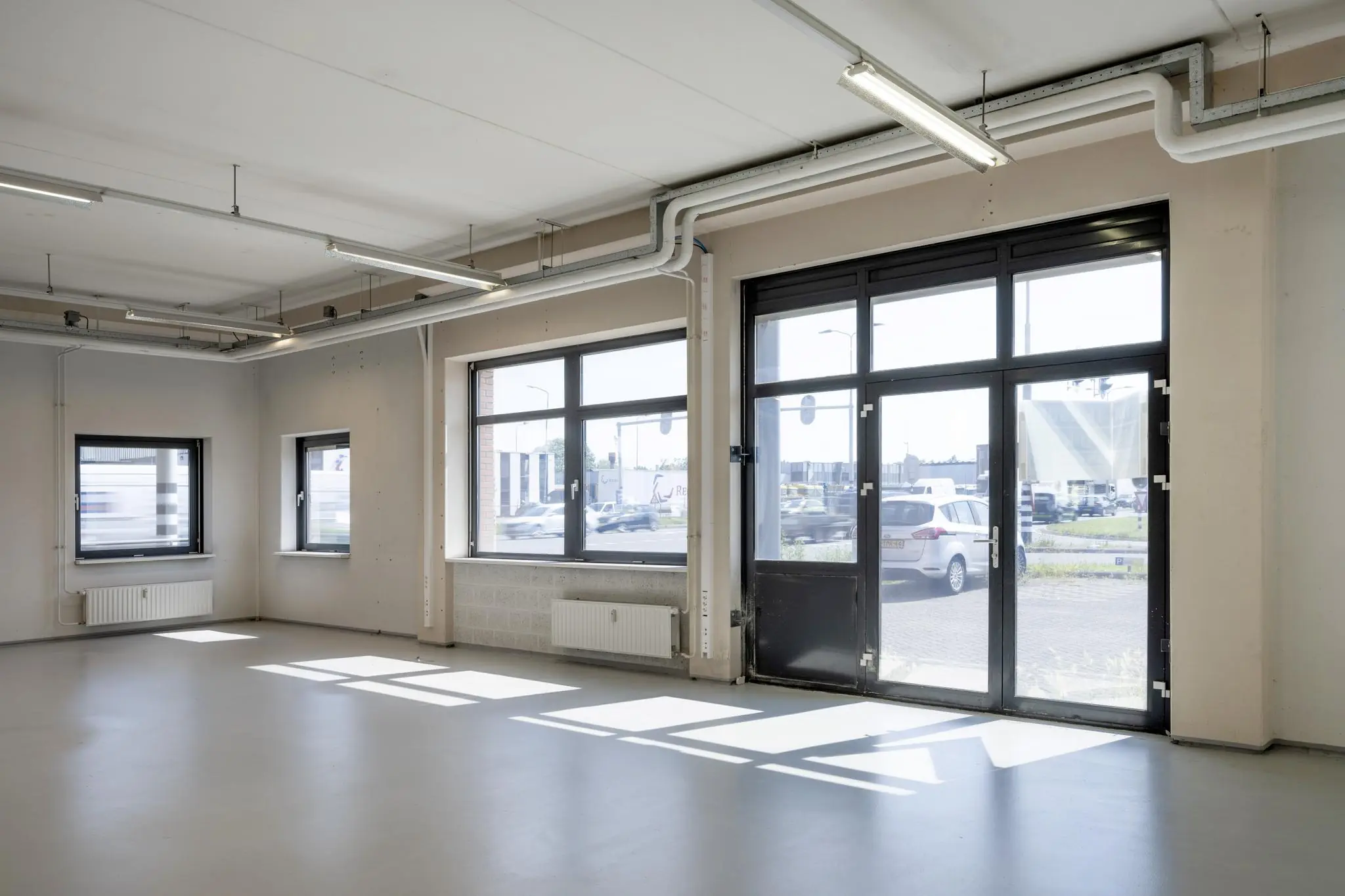 Lichtrijke, lege bedrijfsruimte aan de Breguetlaan met grote ramen en industriële details.