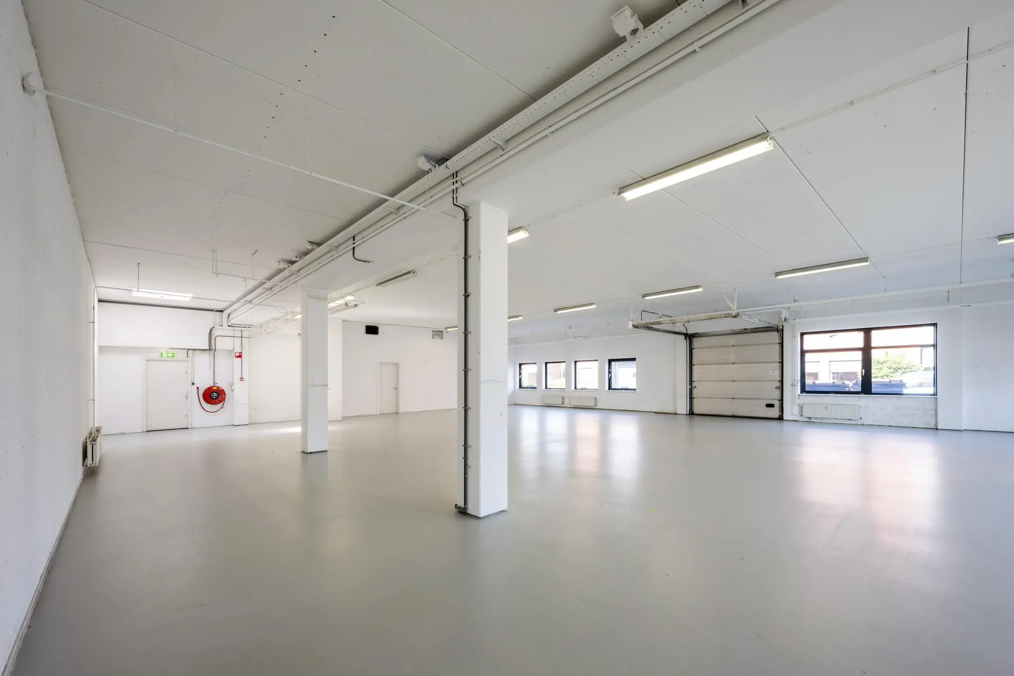 Leeg industrieel bedrijfs- of magazijnpand aan de Breguetlaan met witte muren, grote ramen en een overheaddeur.