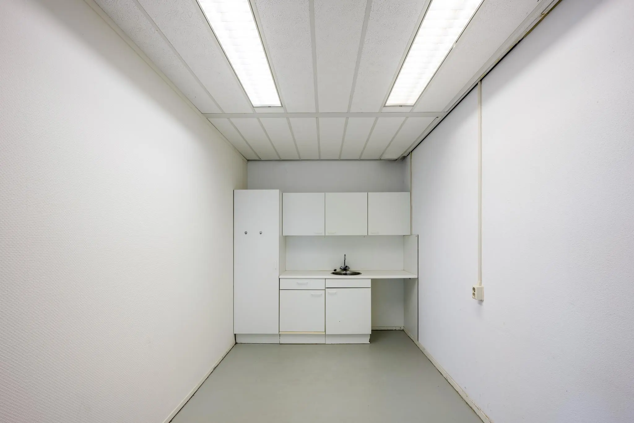 Kleine, eenvoudige pantry met witte keukenkastjes en een gootsteen in een smalle ruimte aan de Breguetlaan.