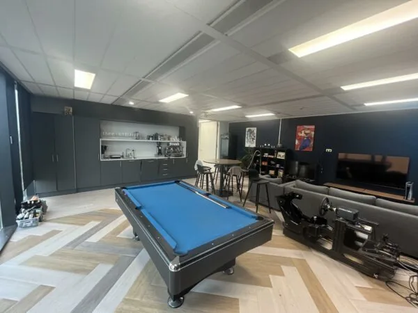 Moderne ontspanningsruimte aan de Winthontlaan met een pooltafel, gamestoelen, zithoek, groot tv-scherm en minibar.