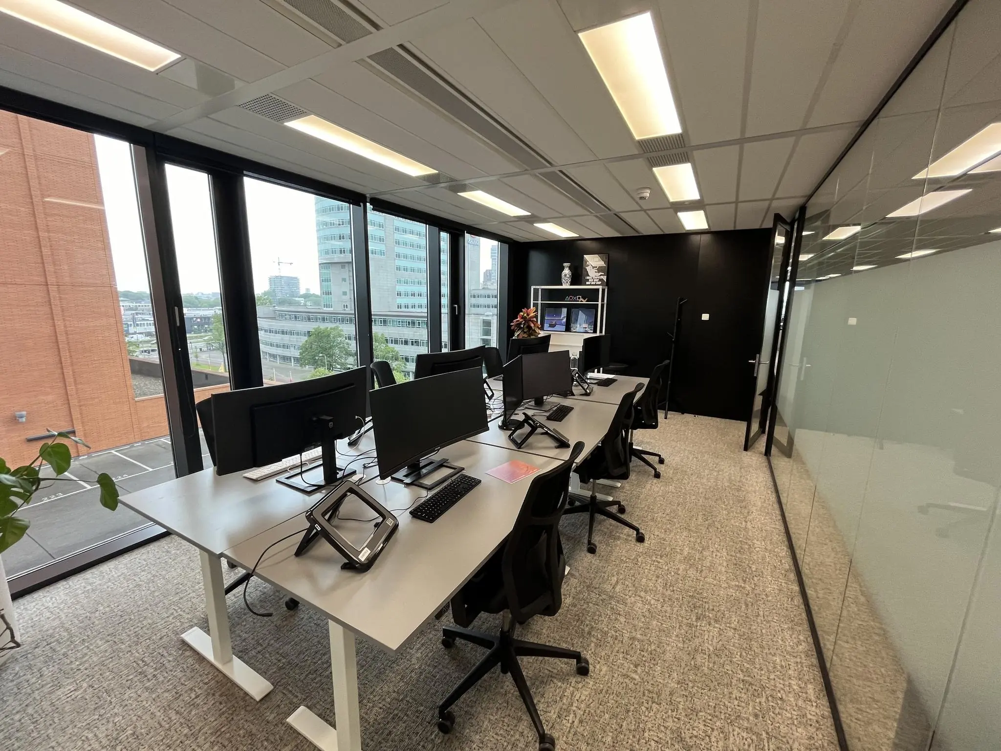 Moderne kantoorkamer aan de Winthontlaan met werkplekken, grote ramen en uitzicht op kantoorgebouwen.