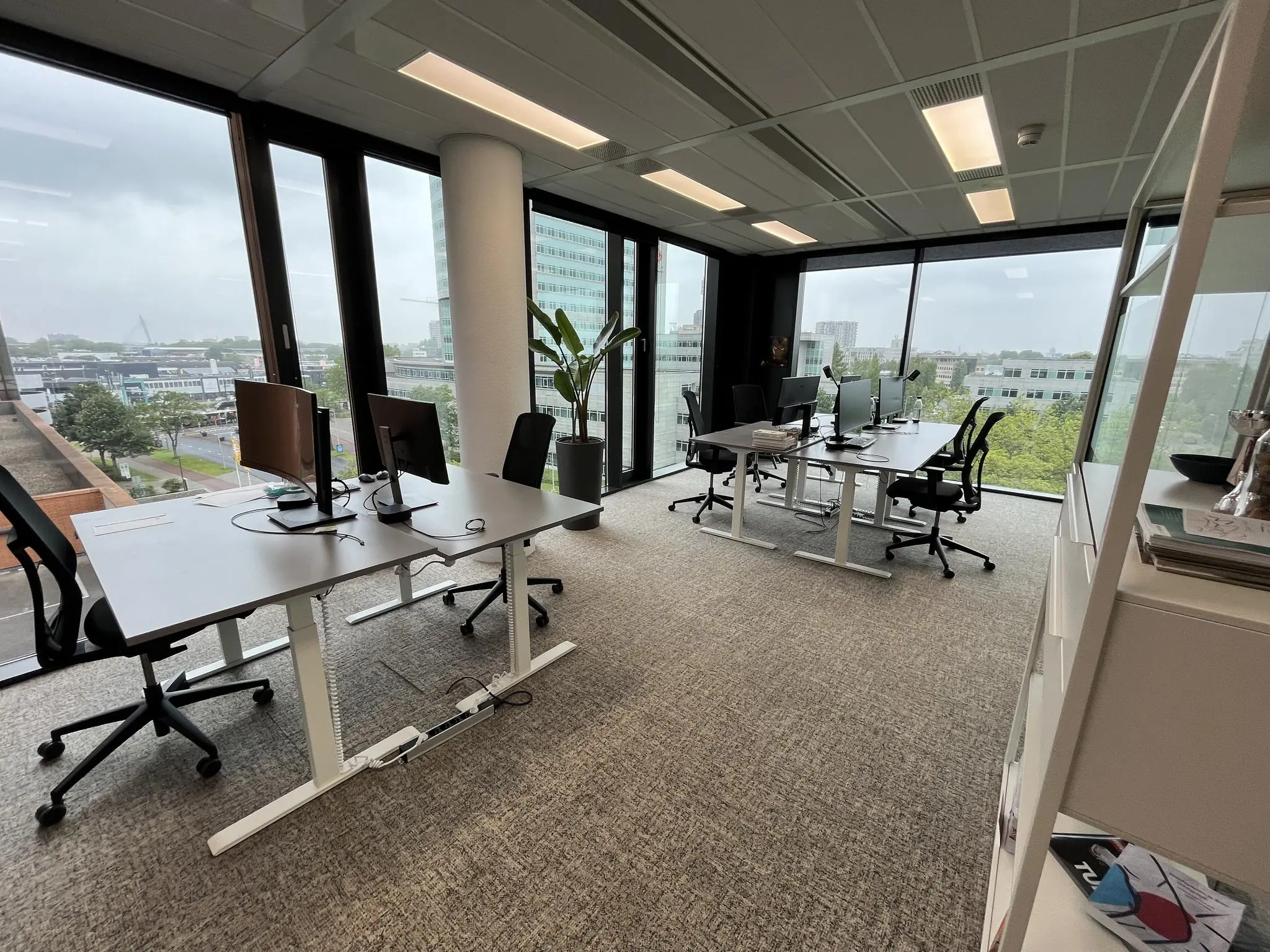 Modern kantoor aan de Winthontlaan met bureaus, computers en uitzicht op de stad door grote ramen.