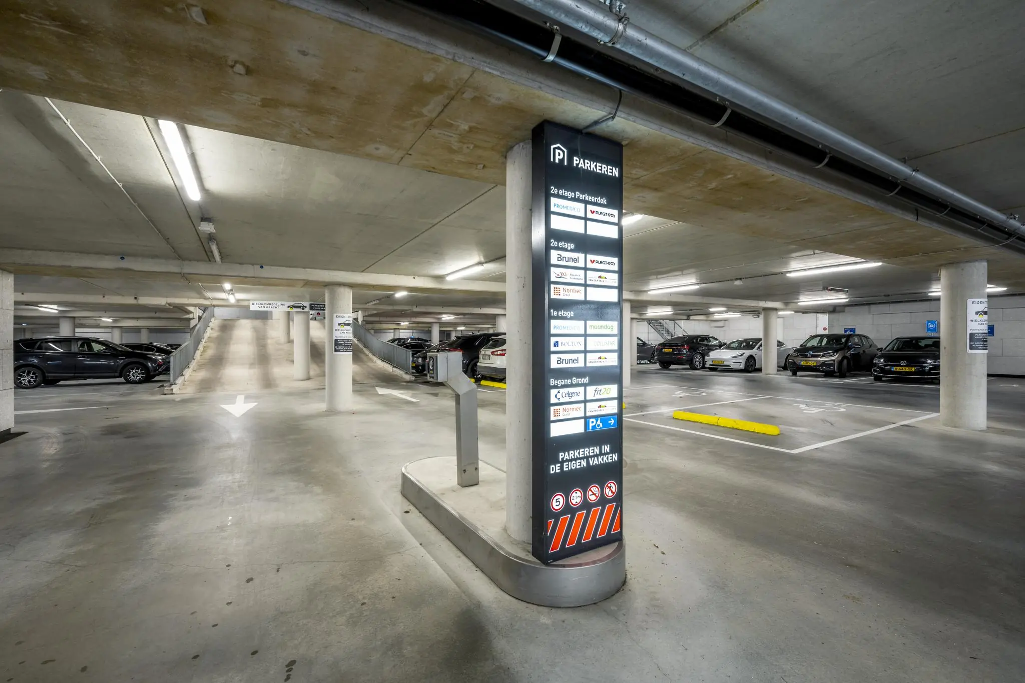Ondergrondse parkeergarage aan de Winthontlaan met geparkeerde auto's en een informatiezuil met bedrijfsnamen.