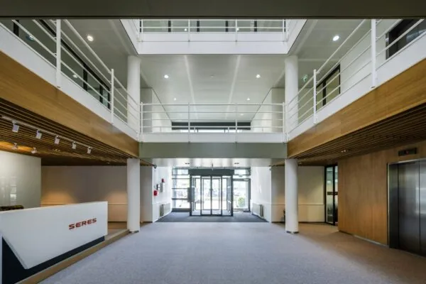 Moderne en lichte entreehal van een kantoorgebouw aan de Burgemeester Stramanweg met een balie van SERES, glazen draaideuren en lift.