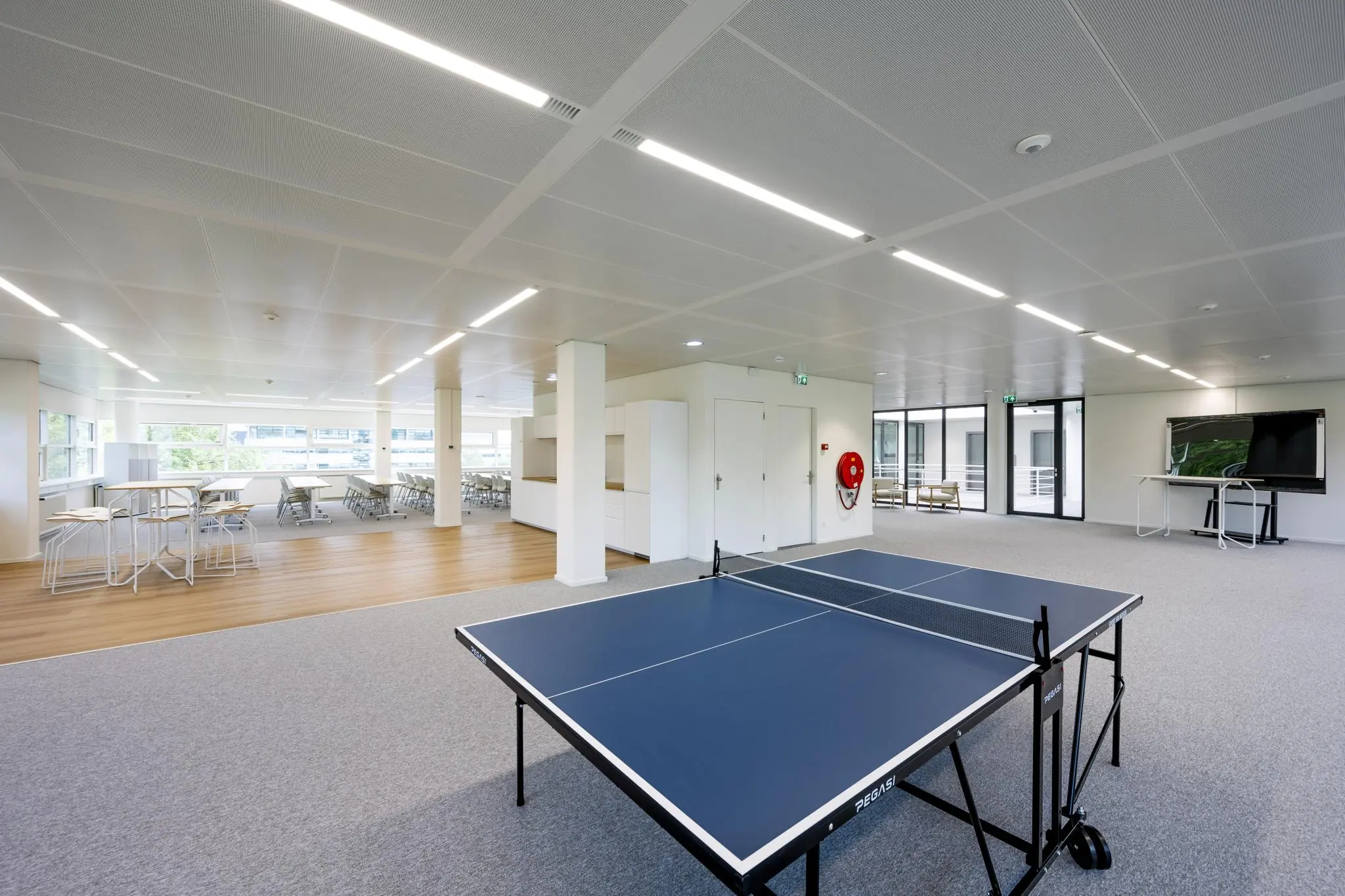 Moderne kantoorruimte aan de Burgemeester Stramanweg met een tafeltennistafel, zitgedeelte en presentatiescherm.