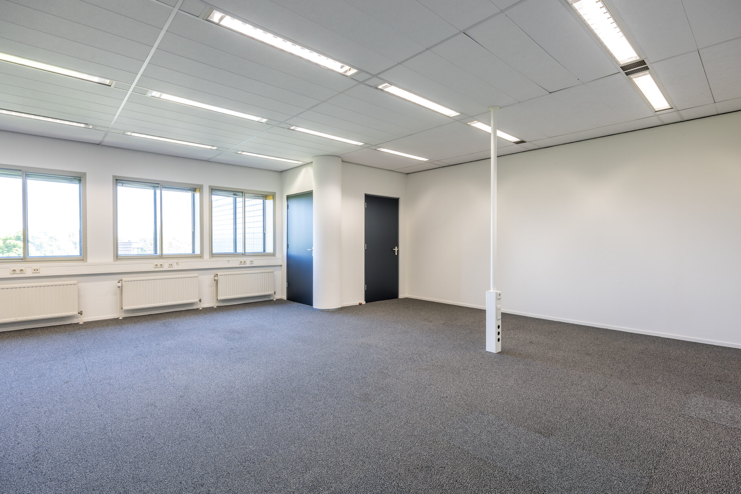 Lege kantoorruimte met tapijt, ramen en twee deuren in Element Offices aan de Goeman Borgesiuslaan in Utrecht.