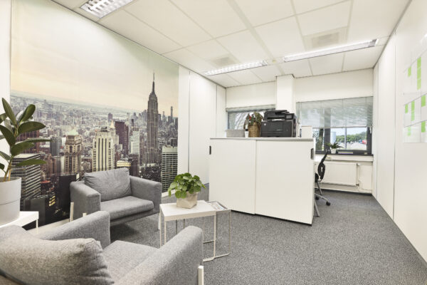 Kleine kantoorunit met grijze stoelen, planten en een groot fotobehang van een stadsgezicht.