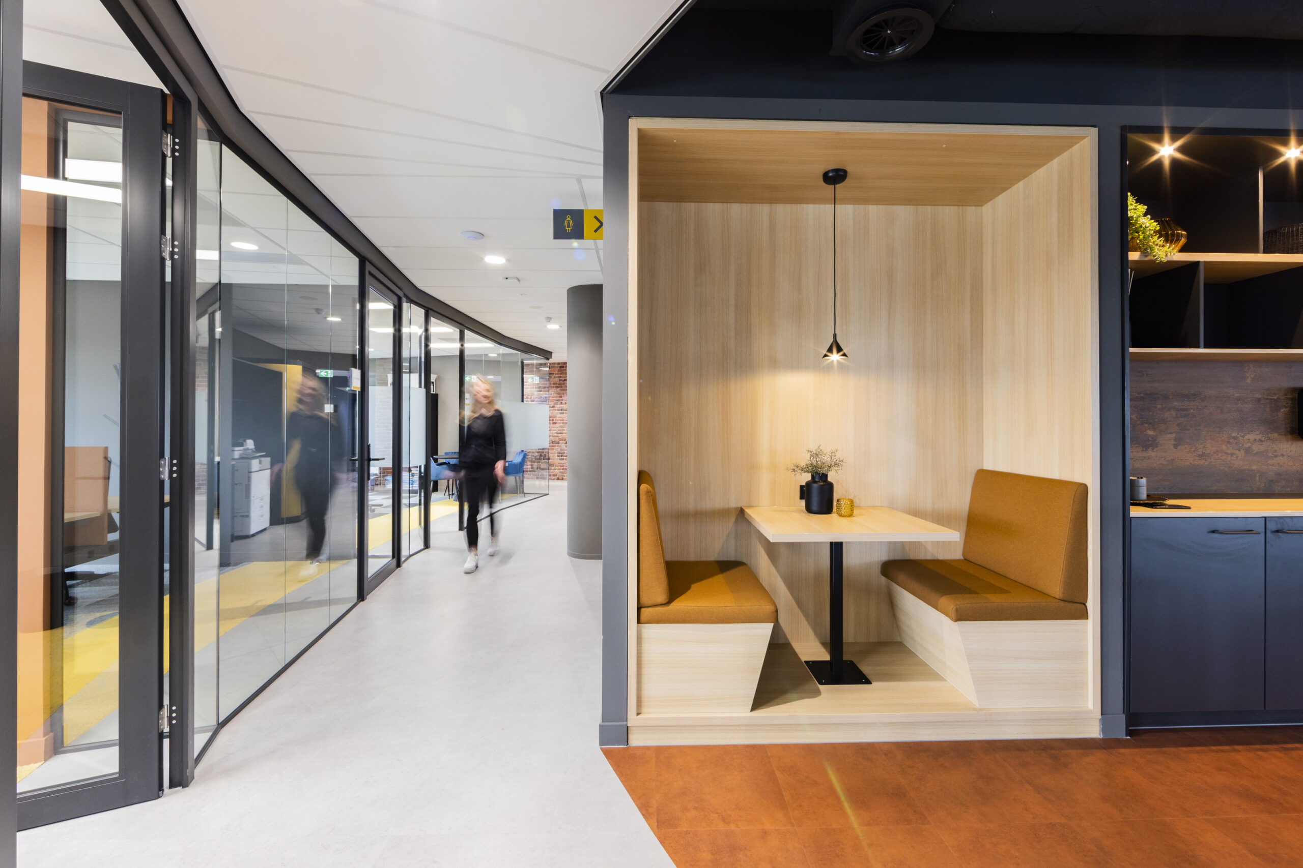 Een moderne kantoorruimte met een houten zitnis en glazen wanden in Rotterdam.