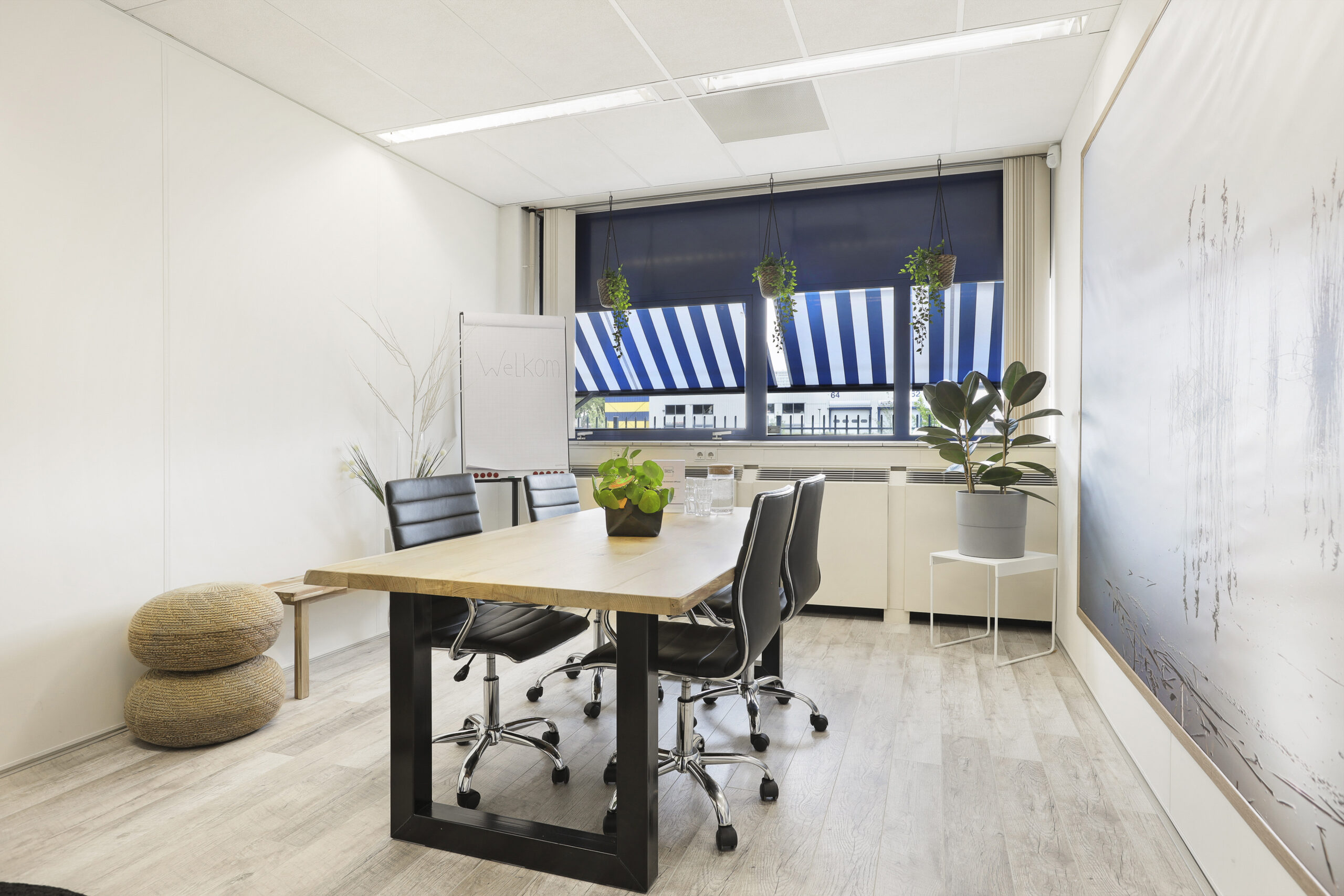 Vergaderruimte met houten tafel, zwarte stoelen en planten bij Element Offices Markerkant in Almere.