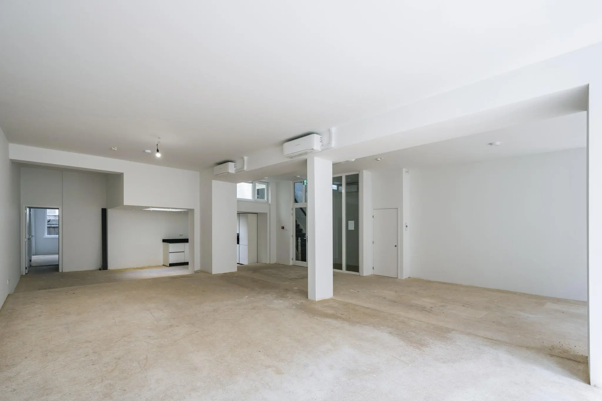 Lichte, lege ruimte met open indeling aan het Damrak, voorzien van pilaren, een kleine keukenhoek en meerdere deuren.