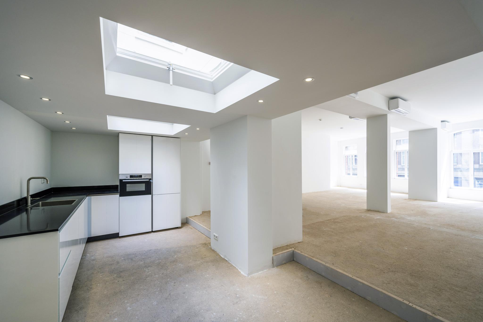 Lichte, ruime verdieping aan het Damrak met een moderne open keuken en grote raampartijen.