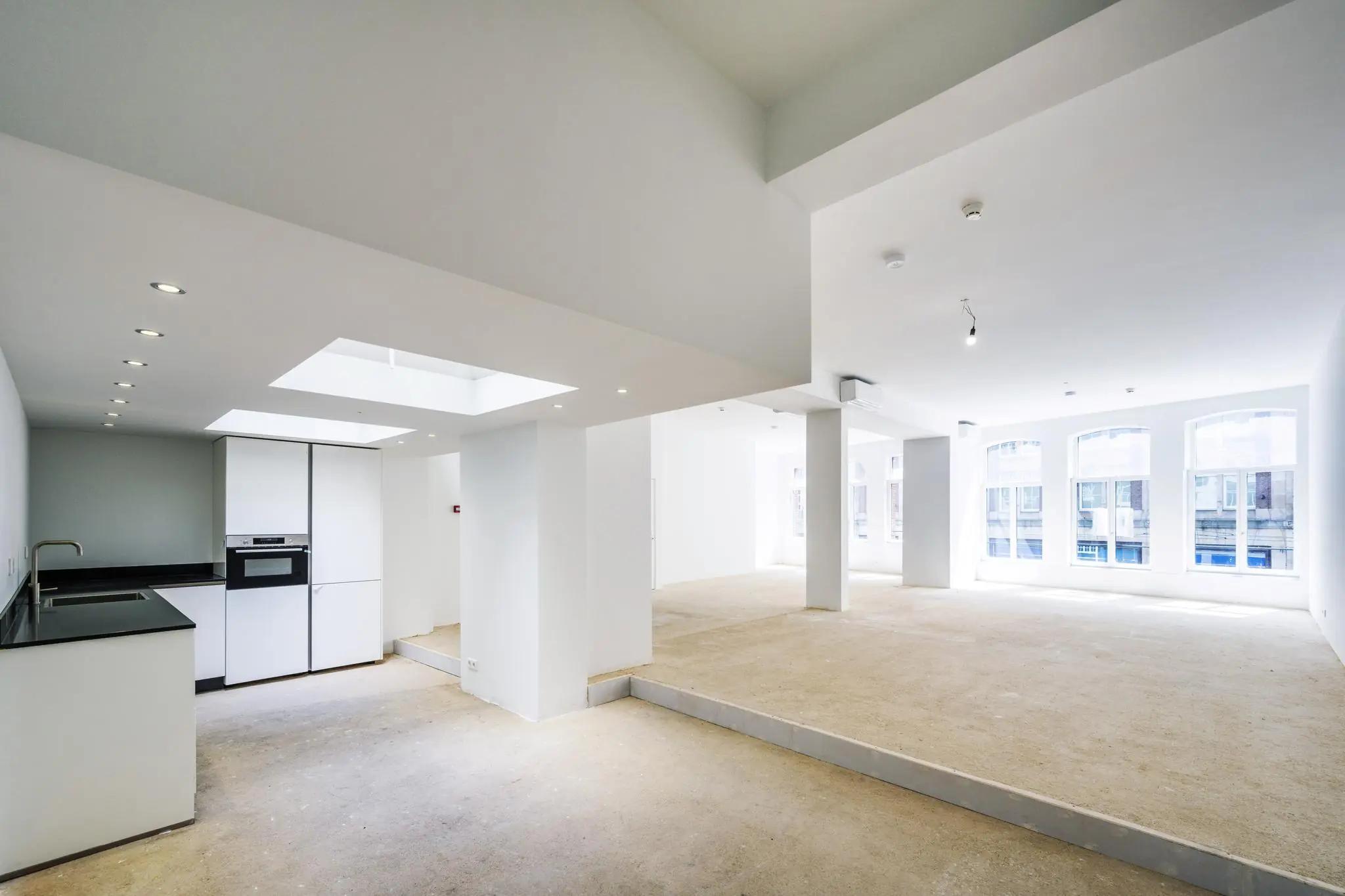 Ruime, lichte casco woonruimte aan het Damrak met open keuken en grote ramen.