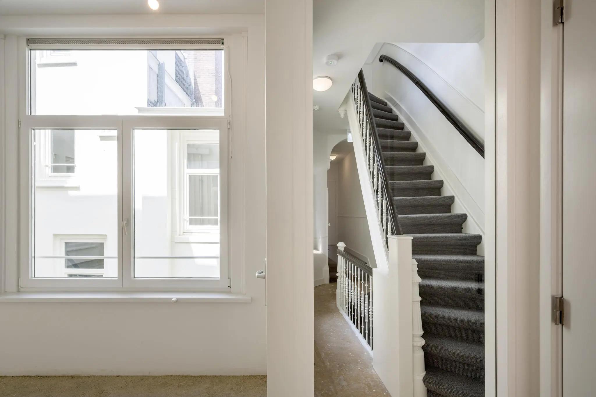 Licht trappenhuis met gestoffeerde trap en groot raam aan het Damrak in Amsterdam.