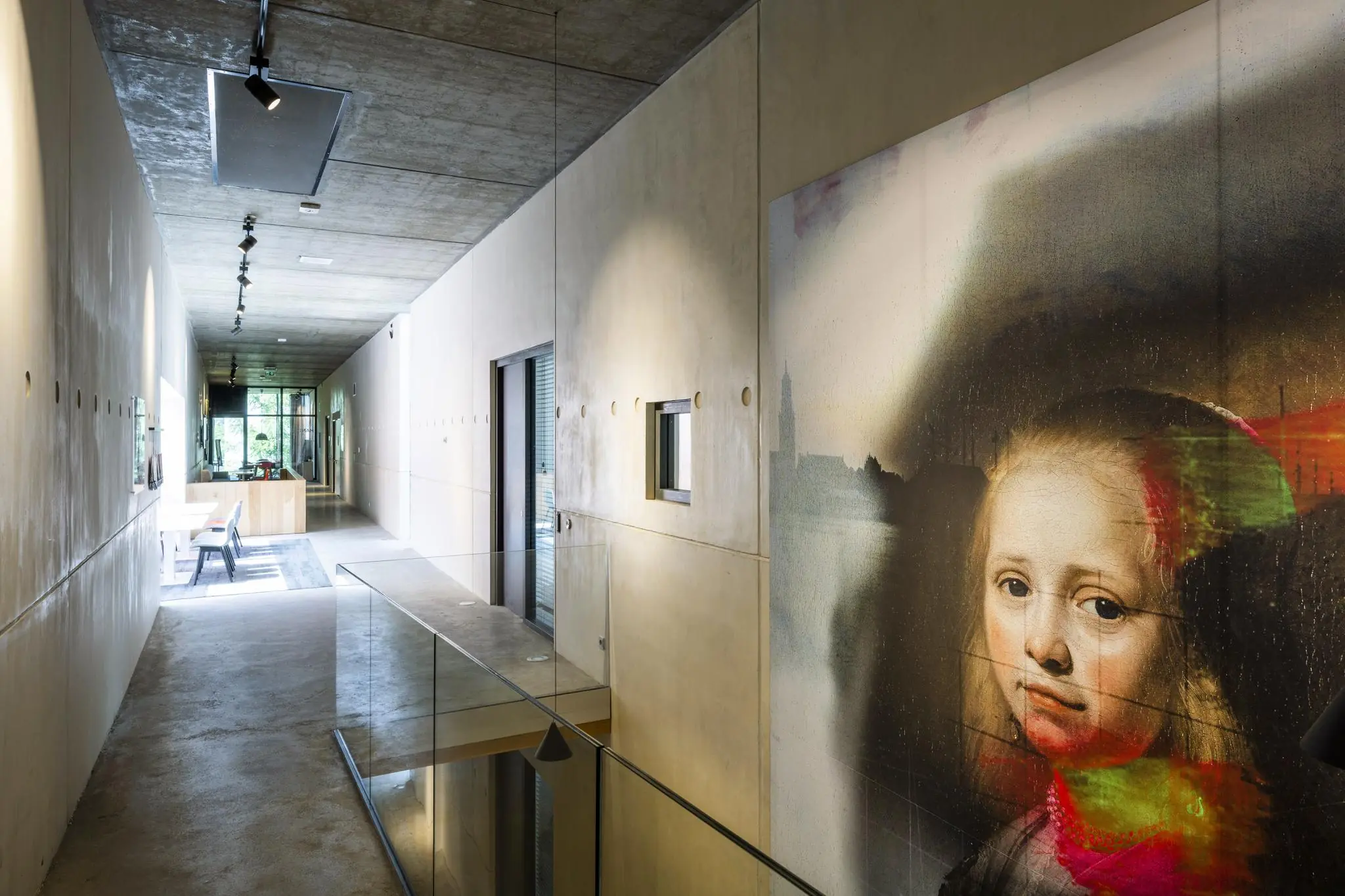 Moderne gang met betonnen plafond en kunstwerk van een meisjesportret aan de muur in een gebouw aan de Fred. Roeskestraat.