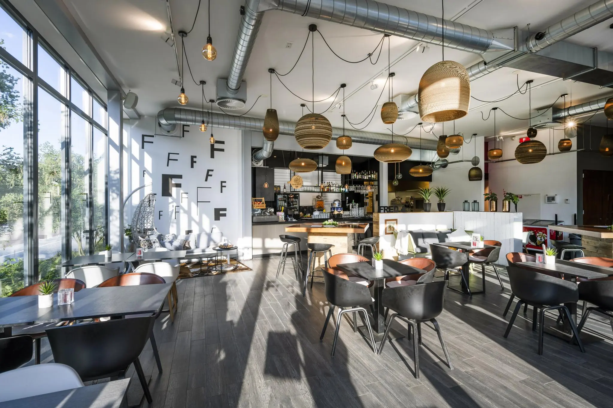 Modern ingericht café-restaurant op de Fred. Roeskestraat met veel natuurlijk licht, houten details en hanglampen.