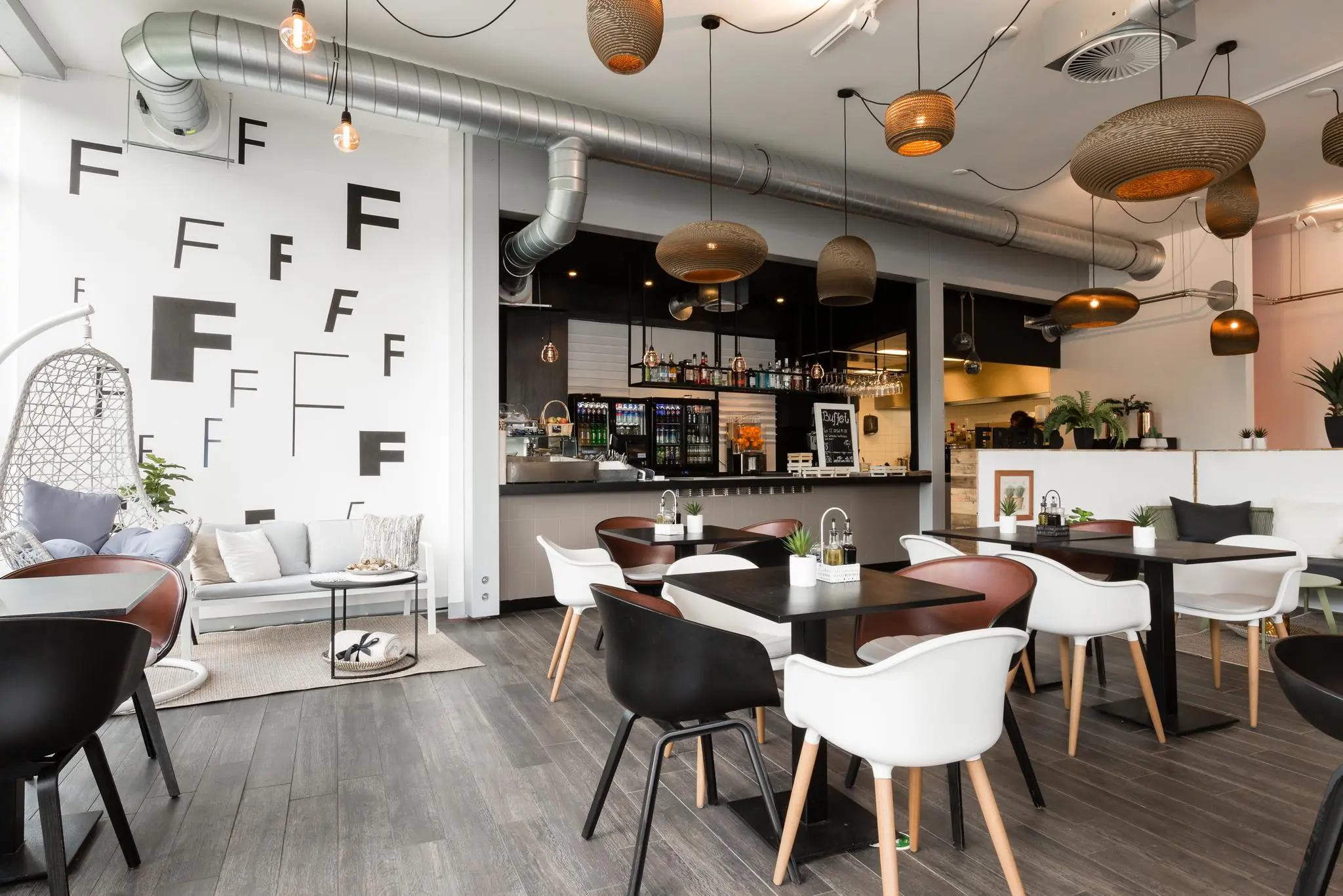 Modern ingericht restaurant aan de Fred. Roeskestraat met stijlvolle meubels, industriële details en een opvallende muur vol met verschillende ‘F’-letters.