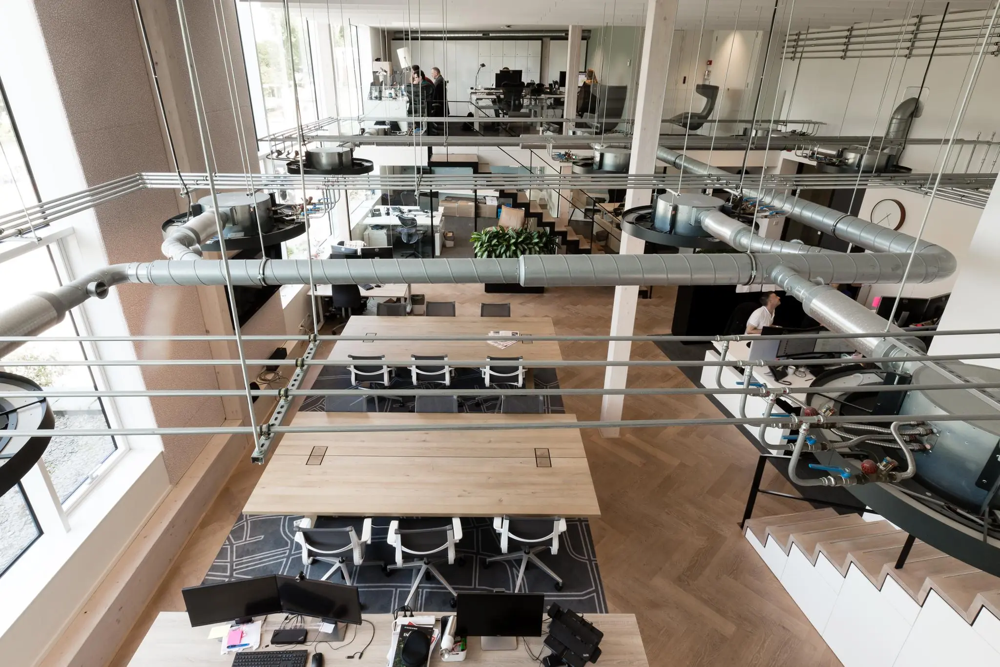 Moderne kantoorruimte aan de Fred. Roeskestraat met open werkplekken, zichtbare ventilatiebuizen en glazen wanden.