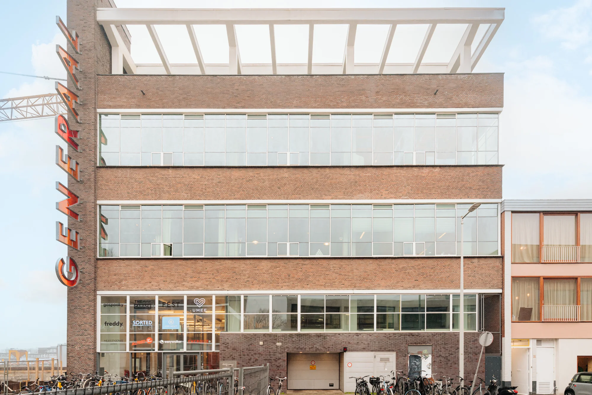 Vooraanzicht van het kantoorgebouw 'Generaal Vetterstraat' met grote ramen en bedrijfsnamen op de begane grond.