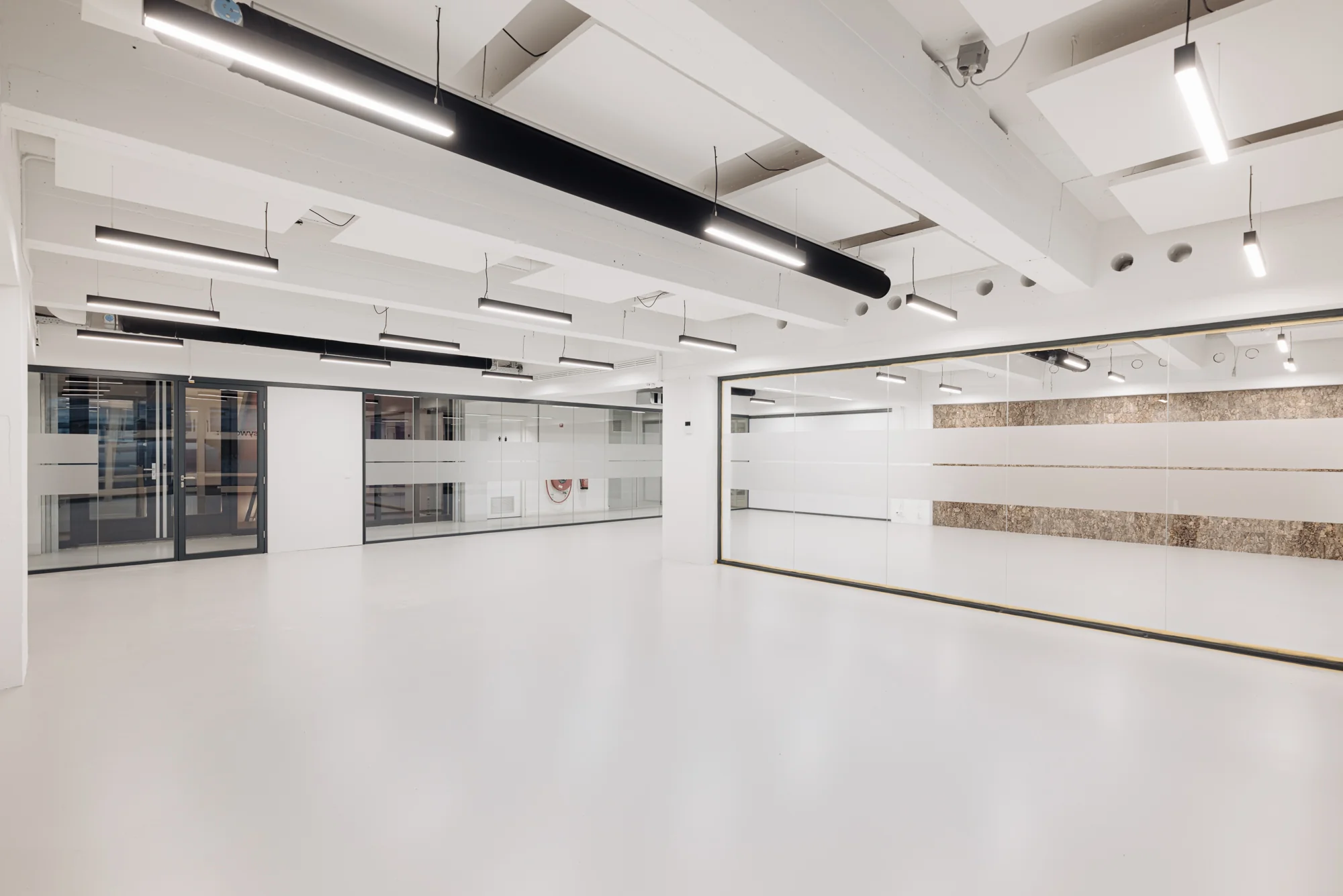 Moderne, ruime kantoorruimte aan de Generaal Vetterstraat met witte vloeren, glazen wanden en strakke verlichting.